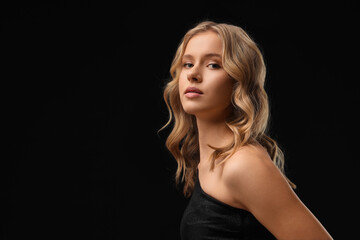 Naklejka premium Blonde young woman with curly hair on dark background