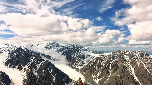 Stunning aerial drone shot of massive snowy mountain peaks in summer.