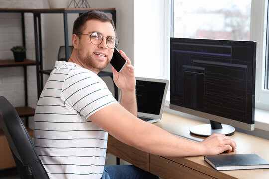 Male programmer talking by phone while working in office