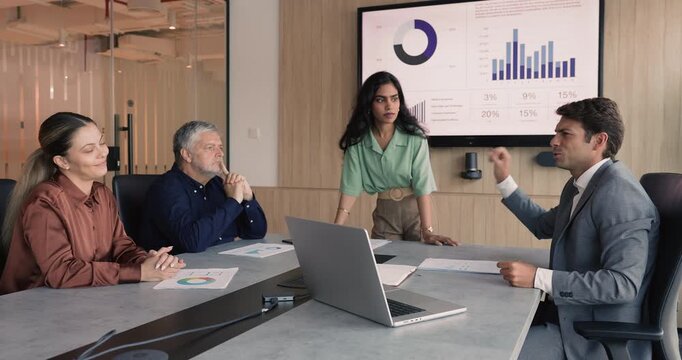 Diverse business team brainstorming on marketing strategy, talking at large meeting table in boardroom, discussing analytic research results. Latin businessman offering ideas to coworkers