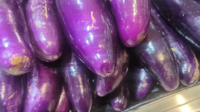 Close-up of fresh purple eggplants stacked together in a market display