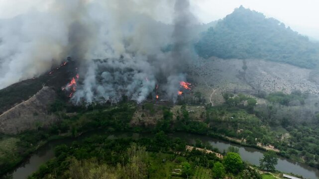 Aerial drone view of a remote tropical forest area with patches of smoke from burning agriculture, rugged mountainous landscape, preparing land for new rice crops, Laos PDR