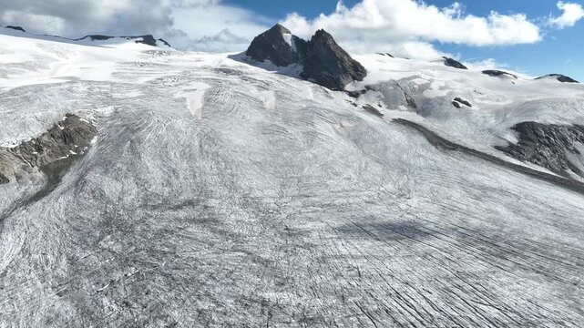 Aerial view of the Rutor Glacier with its vast ice fields and rugged mountain peaks under a blue sky in Aosta Valley, Italy.