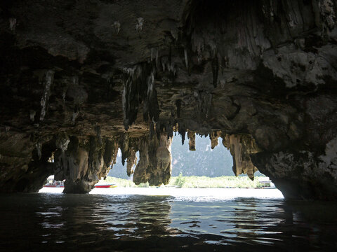 View to the Bright Tropical Island Landscape from the Dark Tham Lot Cave opening framed with hanging stalactites  in in Ao Phang Nga National Park Thailand