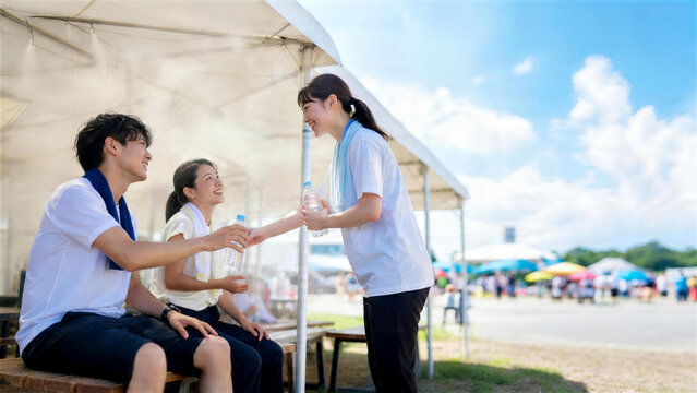 運動後に日陰で水を受け取る学生の熱中症対策