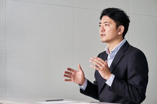 ジェスチャーや身振り手振りで説明をする30代の日本人の男性のビジネスマン
