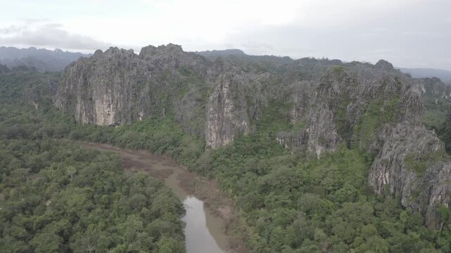 Drone flying over a landscape of limestone cliffs and tropical forest in a national park in Laos PDR.