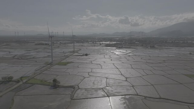 Aerial drone footage of Dam Nai Wind Farm in Khanh Hoa, Vietnam, featuring rows of wind turbines across coastal wetlands, showcasing renewable energy, sustainable power and scenic landscape.