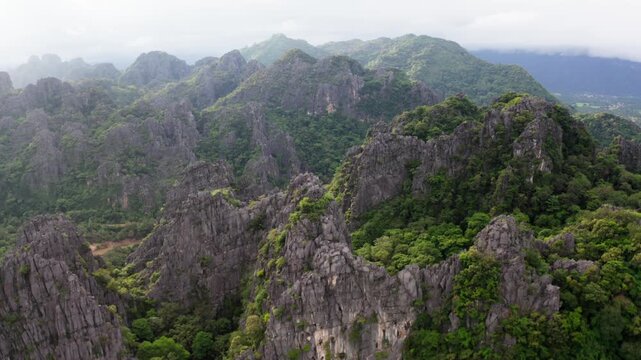 Drone flying over a landscape of limestone cliffs and tropical forest in a national park in Laos PDR.