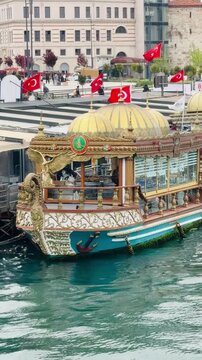 ISTANBUL, TURKEY - MAY 5, 2026: Traditional ottoman style fish restaurant boats docked at Eminonu pier selling famous balik ekmek sandwiches. Golden carved vessels with turkish flags.
