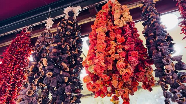 Vibrant traditional Turkish dried red peppers and purple eggplants hanging on ropes at market in Istanbul, Turkey. Organic oriental spices and dry vegetables texture background. Bright.