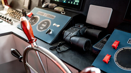 Digital dashboard with navigation monitor system, marine radar, VHF Radio and binoculars in ship captain bridge or boat control room. Wheelhouse steering console on nautical vessel. Boating technology © zephyr_p