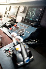 Modern boat dashboard with navigation system, marine radar monitor screen , VHF Radio and binoculars in ship captain bridge. Wheelhouse steering console with blurred throttle control in foreground © zephyr_p