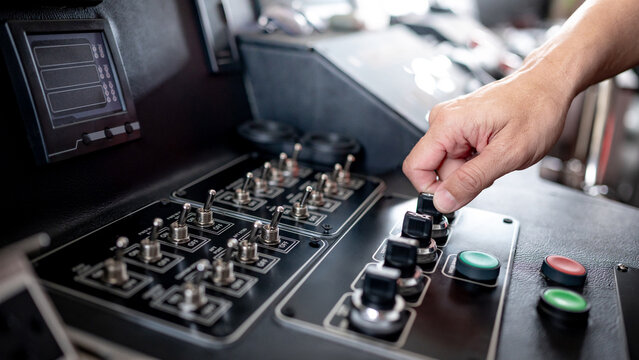 Captain hand turning knob switch near toggle switches and buttons on the boat dashboard. Control panel of vessel transport system. Modern boating technology