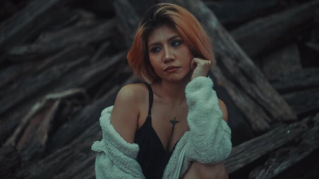 Young woman crouching on weathered driftwood in moody overcast light