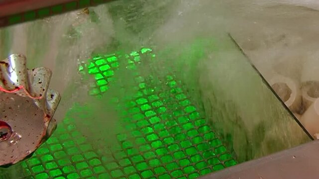 Glimpse a hydro filter actively purifying air. Water swirls vigorously over an illuminated green grid, with air bubbles rising. A metallic impeller aids the cleansing process.