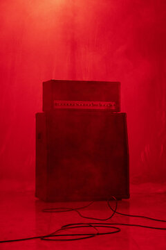 Guitar amplifier stack on stage with dramatic red lighting and smoke