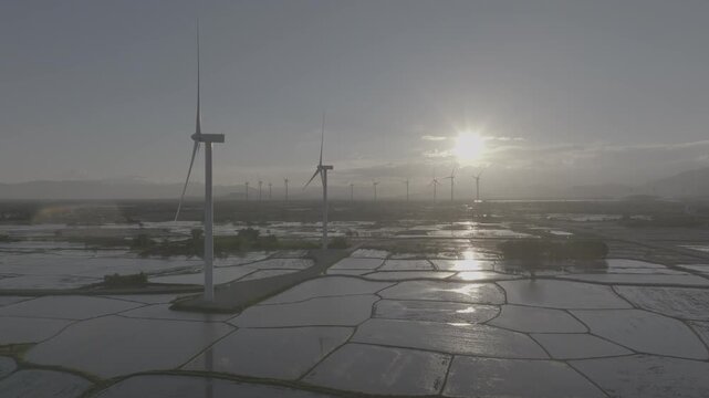 Aerial drone footage of Dam Nai Wind Farm in Khanh Hoa, Vietnam, featuring rows of wind turbines across coastal wetlands, showcasing renewable energy, sustainable power and scenic landscape.