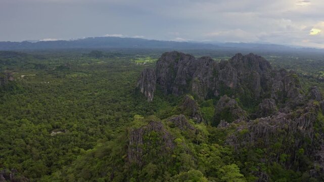 Drone flying over a landscape of limestone cliffs and tropical forest in a national park in Laos PDR.