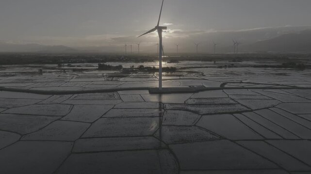 Aerial drone footage of Dam Nai Wind Farm in Khanh Hoa, Vietnam, featuring rows of wind turbines across coastal wetlands, showcasing renewable energy, sustainable power and scenic landscape.