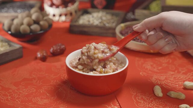 Hand Holding Spoon Over Bowl of Sweet Mixed Bean Rice Porridge