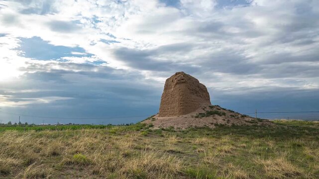 Ancient Earthen Ruin in Grassy Field Under Dramatic Cloudy Sky