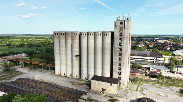 Aerial view of massive concrete grain silos and industrial structures under a clear blue sky in Balchik, Dobrich Province, Bulgaria.