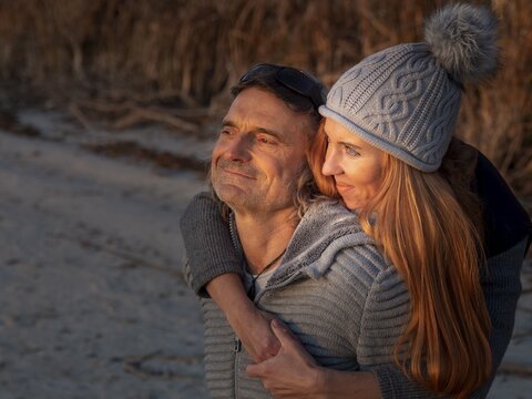 Intimate couple embracing, wearing winter clothes and bobble hat in nature, optimistic view to the horizon, trust in God's creation, Germany