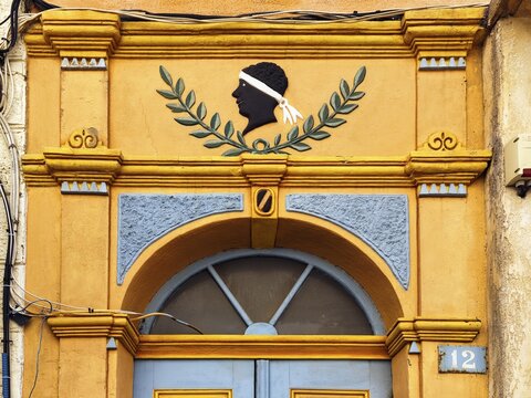 Colourful house entrance, decorated front door, black head with white headband, traditional symbol of the freedom struggle of the Corsicans, t&ecirc;te de maure, detail, old town of L'&Icirc;le-Rousse, Ile Rousse, Corsica, France