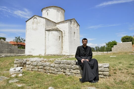 Pastor Župnik don Božo Baričić in front of the Church of the Holy Cross, Crkva svetoga Križa, 9th century, the world's smallest cathedral, Nin, Zadar County, Dalmatia, Croatia