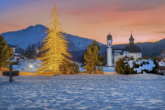 Seekirchl with artificially illuminated winter fir tree and Hocheder 2797m at dusk in winter, Seefeld, Seefeld Plateau, Tyrol, Austria