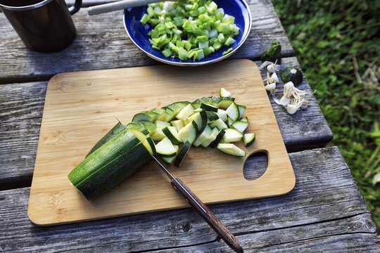 Vegetables on wooden board, courgettes, spring onions, spring onions, sliced, simple camping kitchen, outdoor cooking, camping, outdoors, England, Great Britain