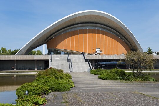 Building with curved roof and wide staircase, surrounded by nature, under a clear sky, House of World Cultures with sculpture Butterfly, former congress hall, John-Foster-Dulles-Allee, Tiergarten, Berlin, Germany