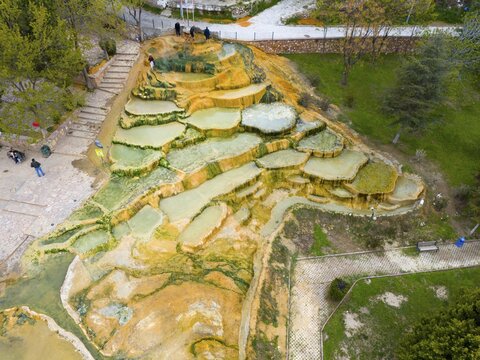 Multicoloured natural mineral terraces with water accumulations in a park landscape, aerial view, Karahayıt Kırmızı Su, Red Spring, Pamukkale, Denizli, Turkey