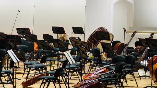 Empty symphony orchestra stage before classical music concert performance. Beautiful string instruments, cellos, double basses and music stands. Elegant cultural event, acoustic performance concept.