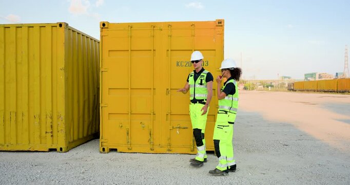 Wide view of adult logistics workers walking beside yellow container row, inspecting cargo door, checking yard inventory, shipment route, safety procedure, freight dispatch workflow onsite duty
