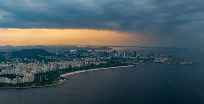 Dramatic aerial view of Rio de Janeiro cityscape under dark cloudy sky at dawn. tranquil coastline along sea