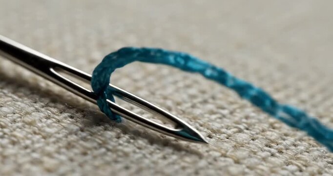Sewing needle with blue thread closeup.
