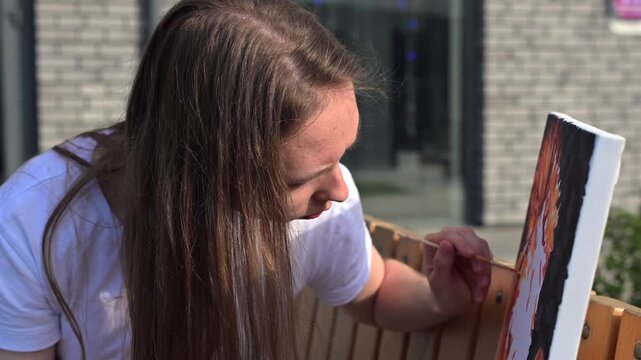 A Caucasian woman with mild cerebral palsy paints by numbers outdoors