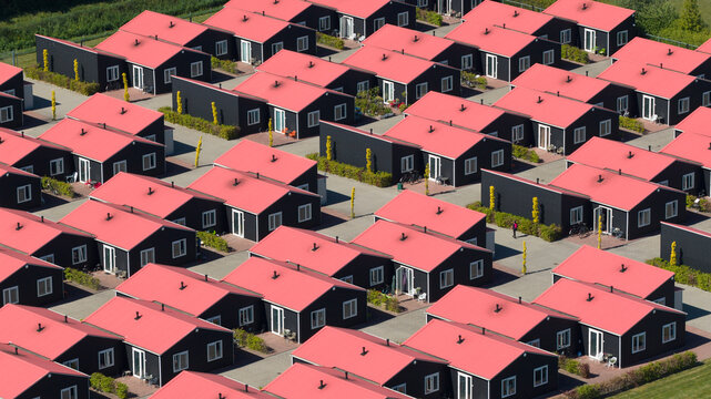 Aerial view of modern residential houses with distinctive red roofs and black walls arranged in a geometric pattern Luttelgeest, Flevoland, Netherlands.