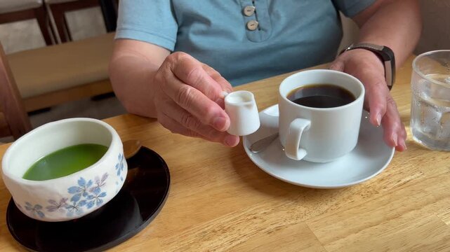 コーヒーにフレッシュを入れる高齢女性