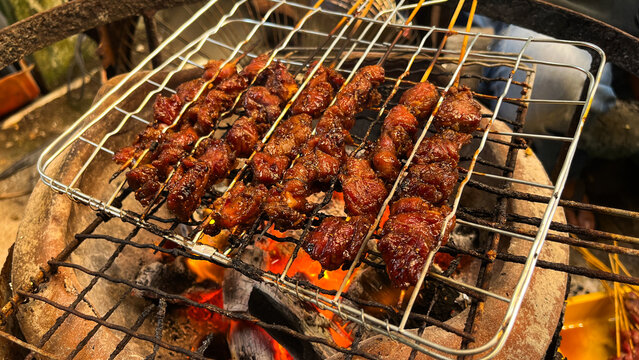 close up view of goat or beef satay grilled over a fire and charcoal. grilling tool. eid al adha, idul adha. sate kambing, sapi. indonesian food or culinary. 