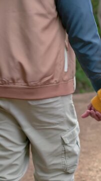 Vertical video: Reaching hands, couple walking forest trail, exploring woods with beanie and scarf