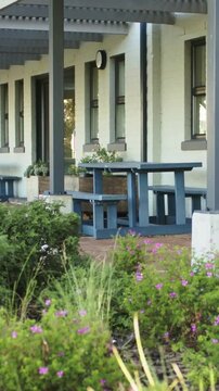 Vertical video: Panning camera focusing on blue picnic table with bench on porch, for quiet seating