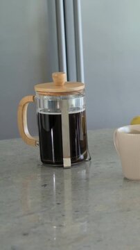 Vertical video: Panning cam right showing French press cup banana berries on stone counter for meal