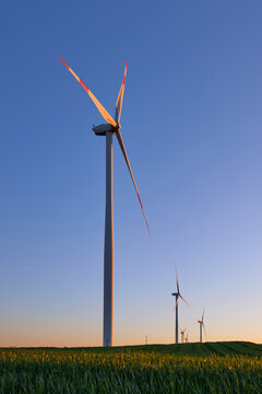 Wind turbines at sunset in green field &ndash; renewable energy, clean power, sustainable future.