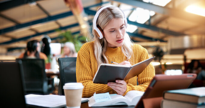 Student, reading and book with headphones in library for higher education, learning or studying. Woman, academic learner or writing with notebook or research for knowledge, assignment essay or thesis