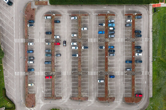 Aerial view of an organized parking lot with parked cars, asphalt surface, and pedestrian crossings in Leccio, Toscana, Italy.