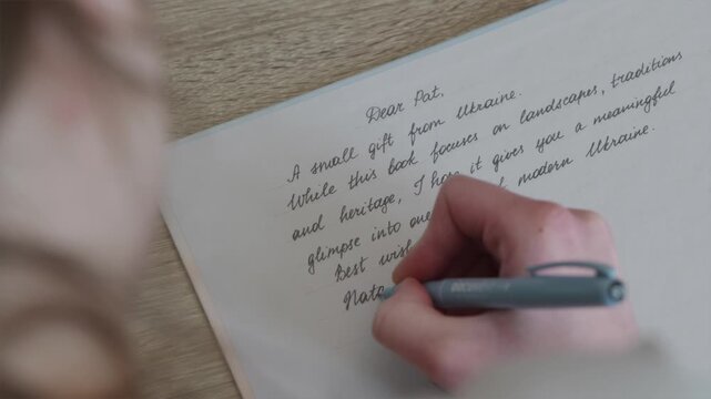 Young woman handwriting a personal letter to a friend on book flyleaf