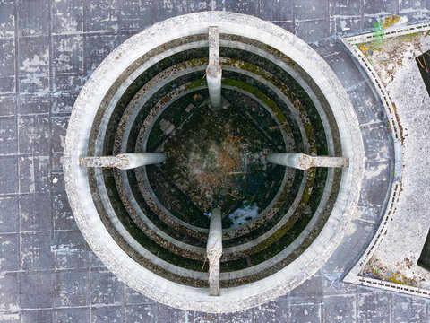 Aerial view of a circular concrete structure with concentric rings and pillars on a tiled rooftop in Leccio, Toscana, Italy.